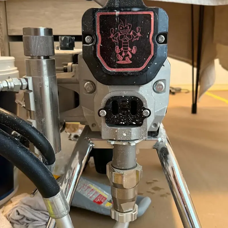 Airless paint sprayer set up on a protected floor