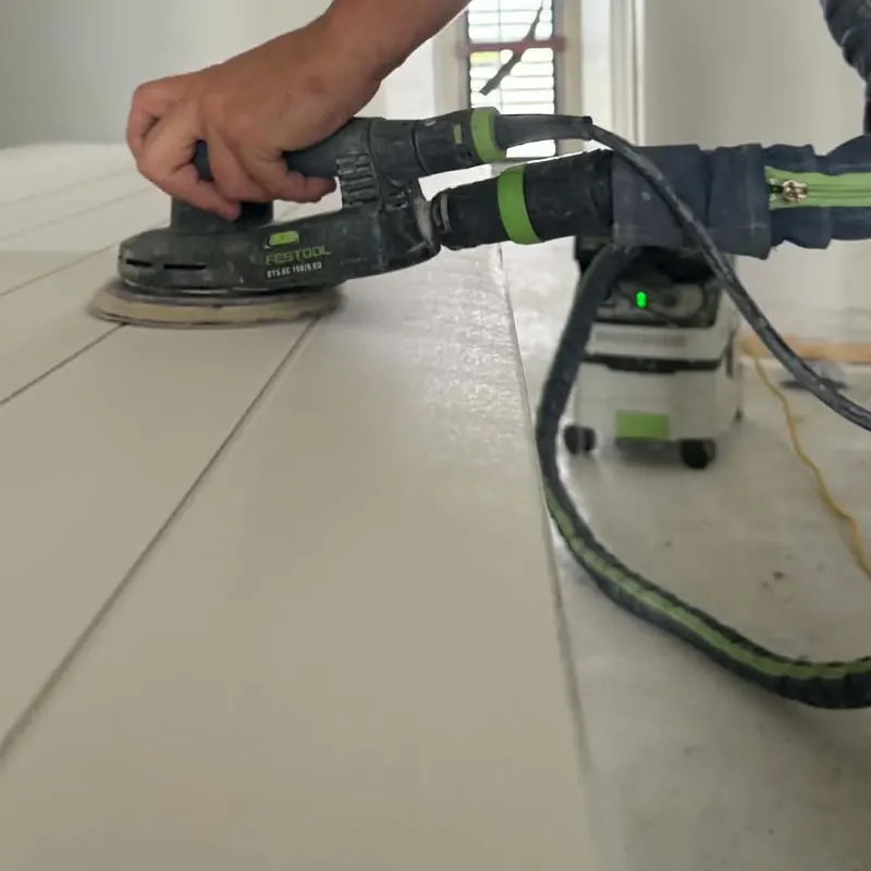 Festool sander with dust extractor attached, sanding a panelled door
