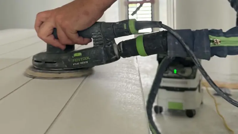 Festool sander with dust extractor attached, sanding a panelled door