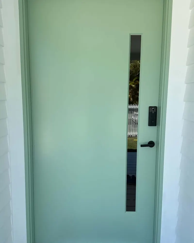Front door and frame painted in soft green, with a slim glass panel